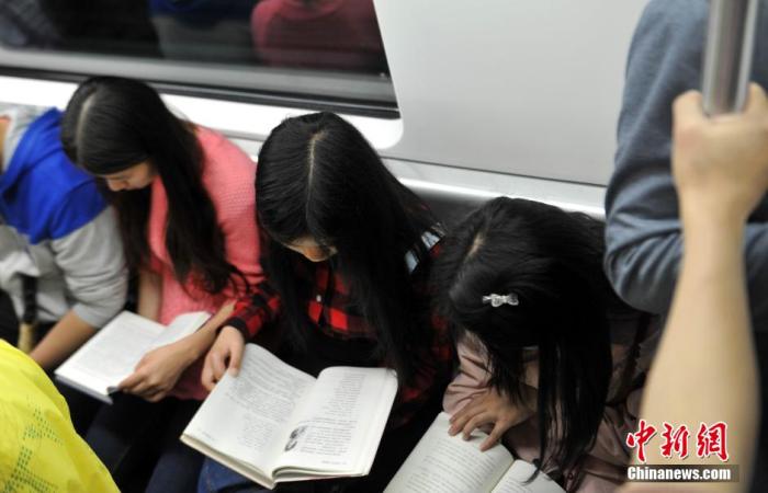 资料图：南昌高校学生在地铁上共同阅读书籍。刘占昆 摄