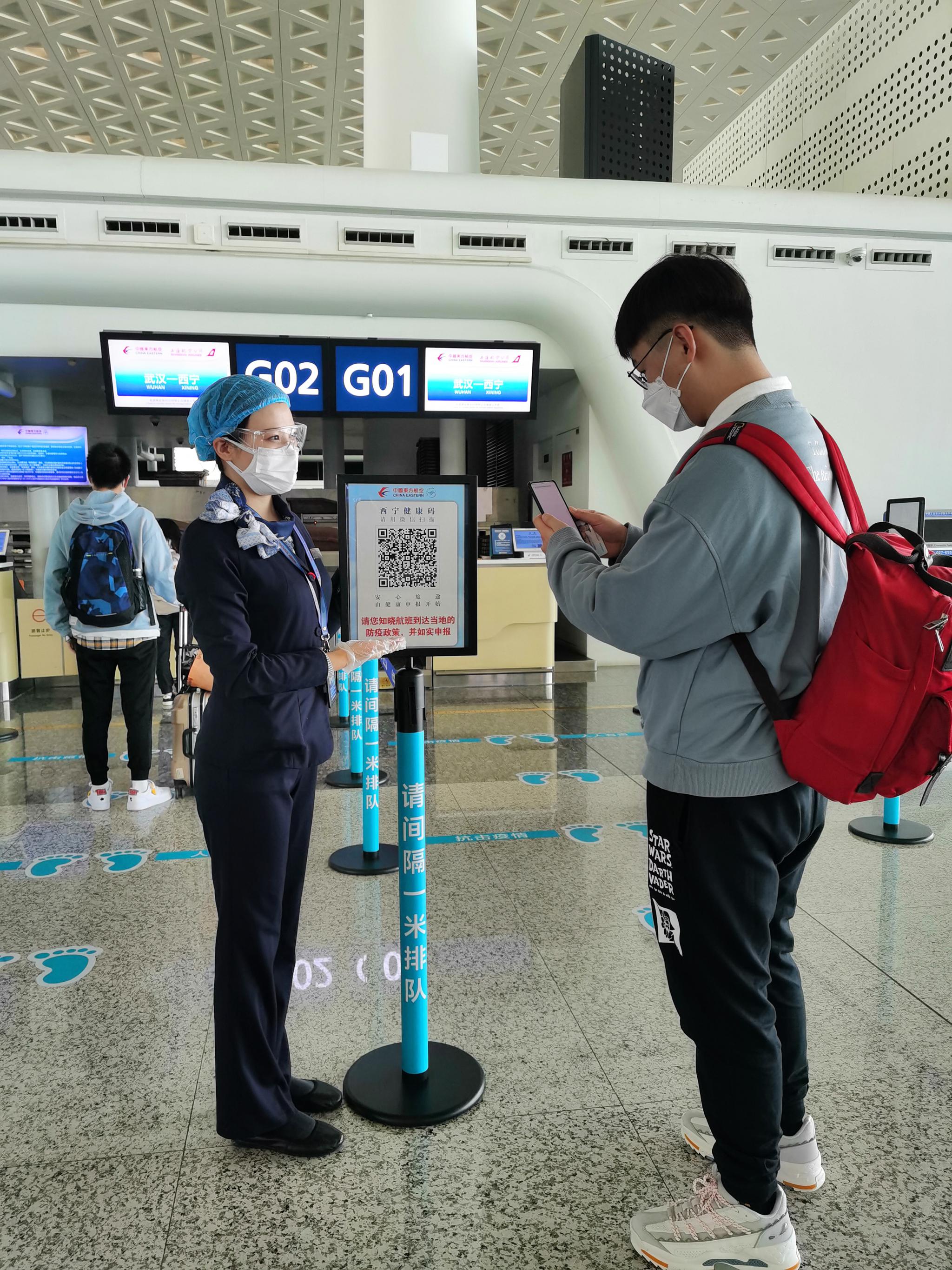 航空公司地面事情职员辅助大门生举行“康健绿码”认证。东航供图