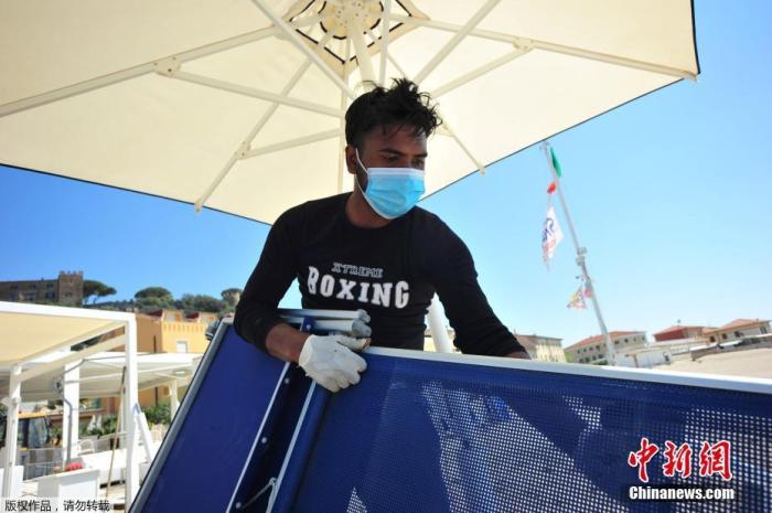 当地时间4月24日,意大利一海滩俱乐部的工人戴着口罩和手套为度假区的重新开业做准备。意大利总理孔特表示,从5月4日开始,该国将正式进入抗疫第二阶段,重启全国经济。