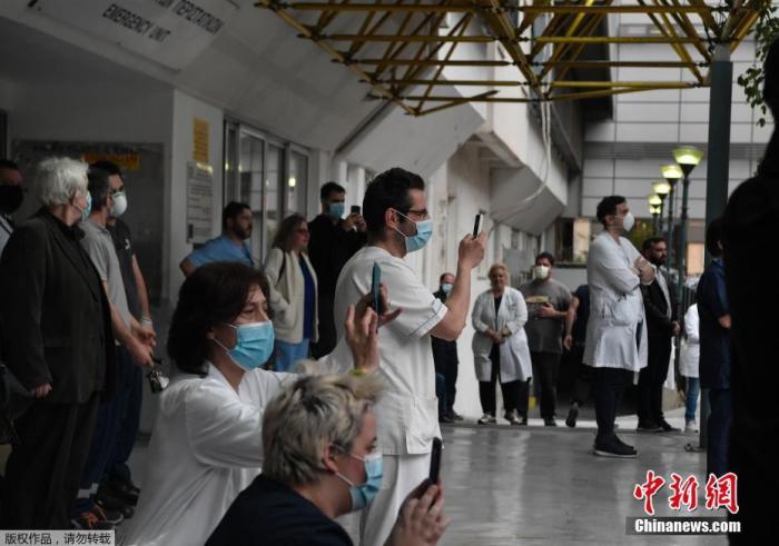 当地时间4月20日,希腊雅典福音医院的医务人员在院子里聆听希腊国家广播交响乐团的音乐会。图为医护人员在欣赏表演。