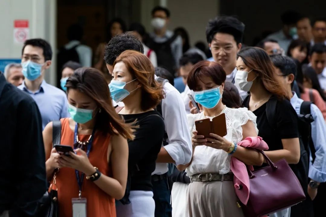 人们在新加坡中央商务区的办公楼外排队等候测温,图源彭博社
