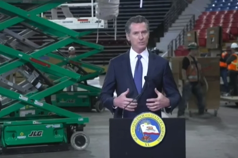 纽森6日举行发布会，背景是萨克拉门一家正被改造成医院的篮球馆 视频截图