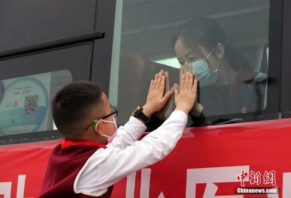 四川省支援湖北医疗队所有队员全部平安返程，一位医疗队队员在大巴上与儿子隔窗相望。中新社记者 王磊 摄