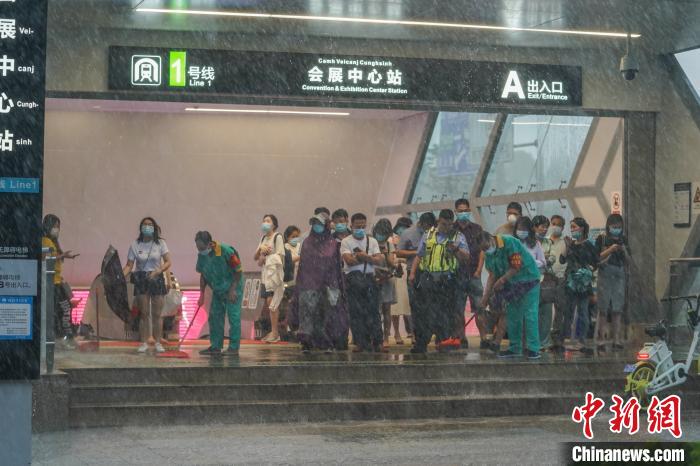 图为市民在地铁口避雨。 陈冠言 摄