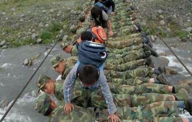 ▲2008年6月,四川省地动灾区彭州市湔江河畔,兵士趴在还没有修完的铁索桥上,构成暂时的“人桥”,让小门生们从本身的脊背上爬过。