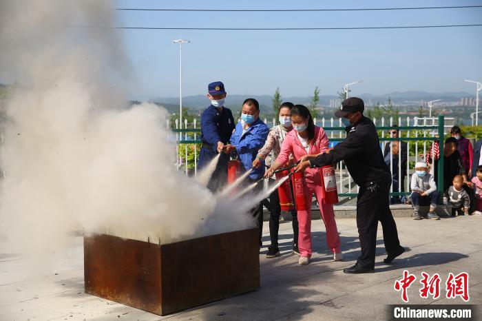 图为救火员正在引导十堰市郧阳区青龙泉社区事情职员和住民利用灭火器扑救油池火警。蒋锋 摄