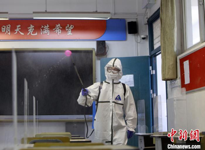 图为救火员正在对武汉市粮道街中学课堂举行周全消杀。王方摄