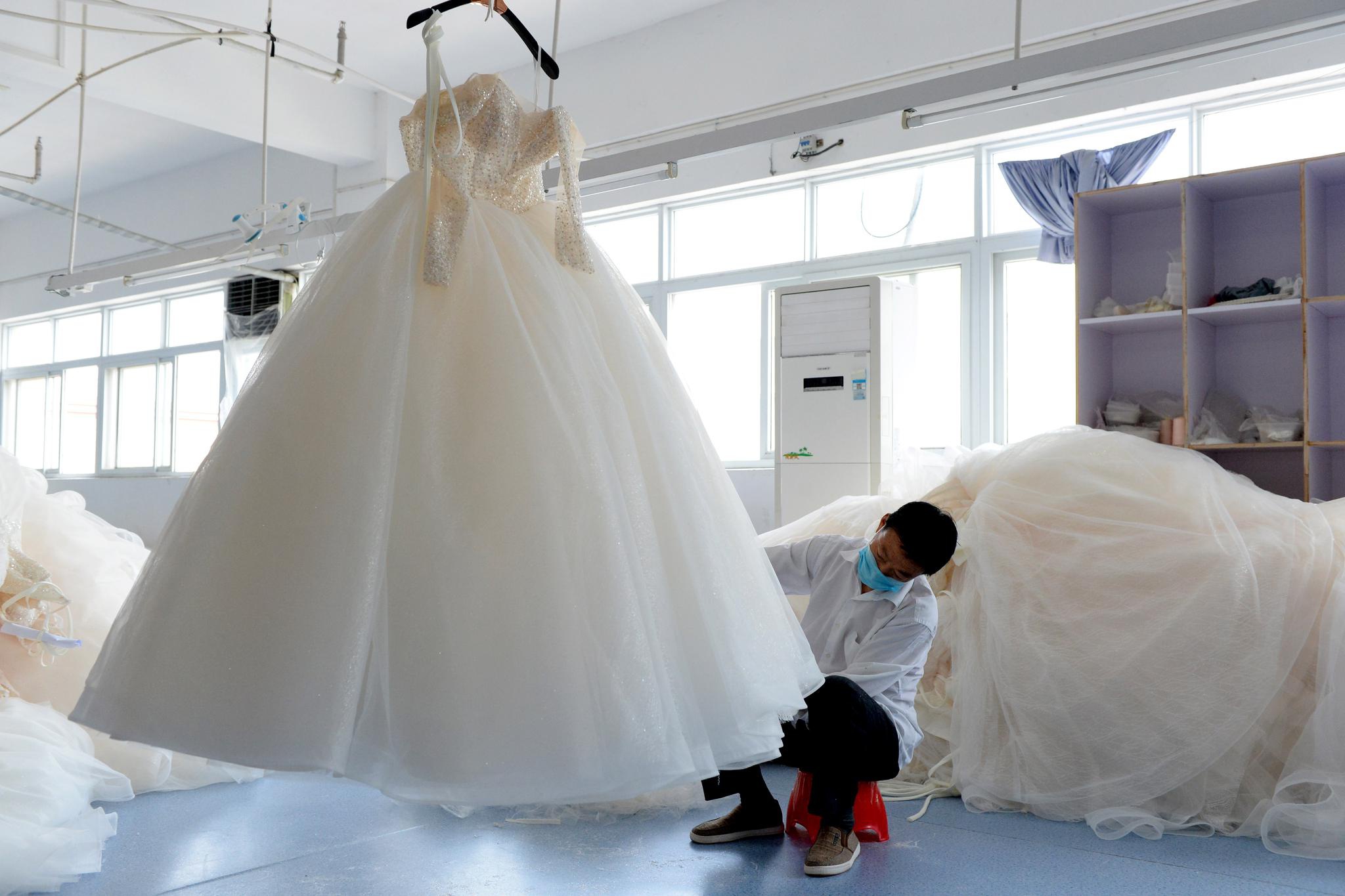 4月30日,工作人员在安徽六安市丁集镇的一家婚纱生产企业内修剪婚 