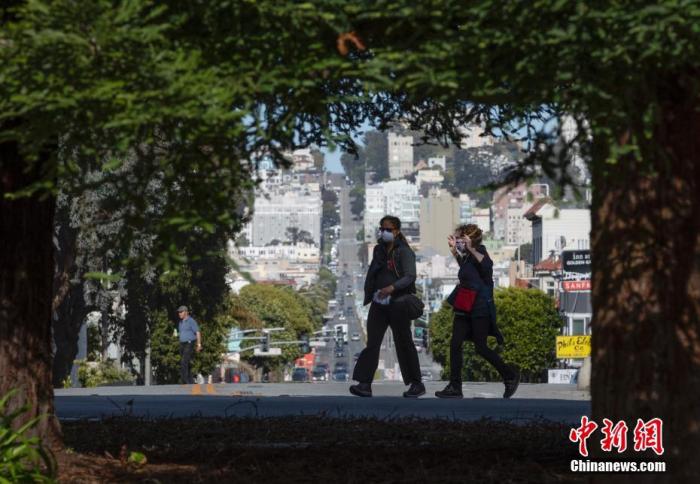 当地时间4月27日,美国旧金山市民经过一条空荡的马路。中新社记者 刘关关 摄