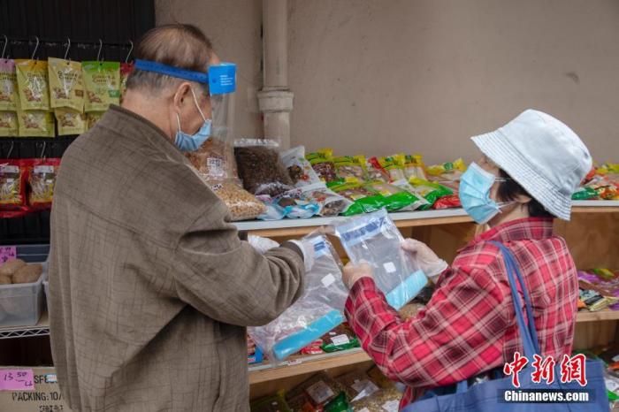 当地时间5月18日，一位老人在美国旧金山华埠一处店铺外的摊位前购买防疫物品。中新社记者 刘关关 摄