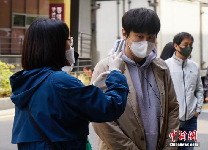 在韩国首尔一投票站,投票者接受体温检测。 中新社记者 曾鼐 摄