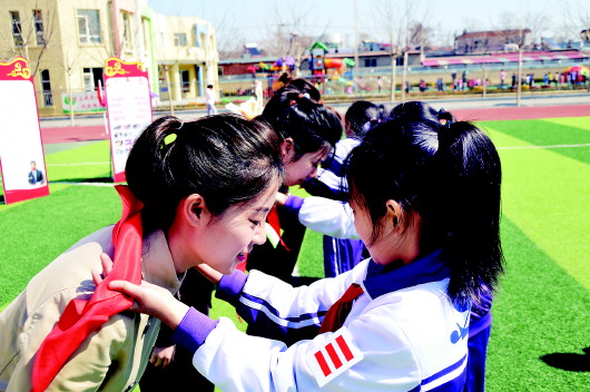  汤池镇中心小学学生为高潘（左）系红领巾。（受访者供图）