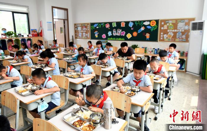 成都石室天府中学附属小学校长唐宇在教室里陪学生共用午餐。　安源 摄