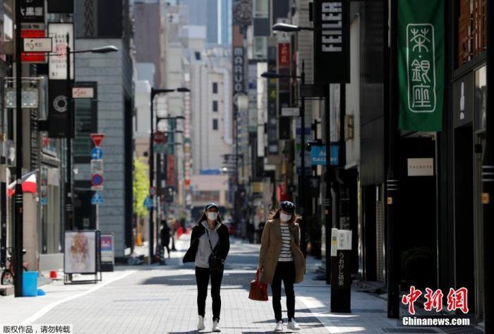 当地时间4月25日,日本东京,戴口罩的女士走过空无一人的购物区。