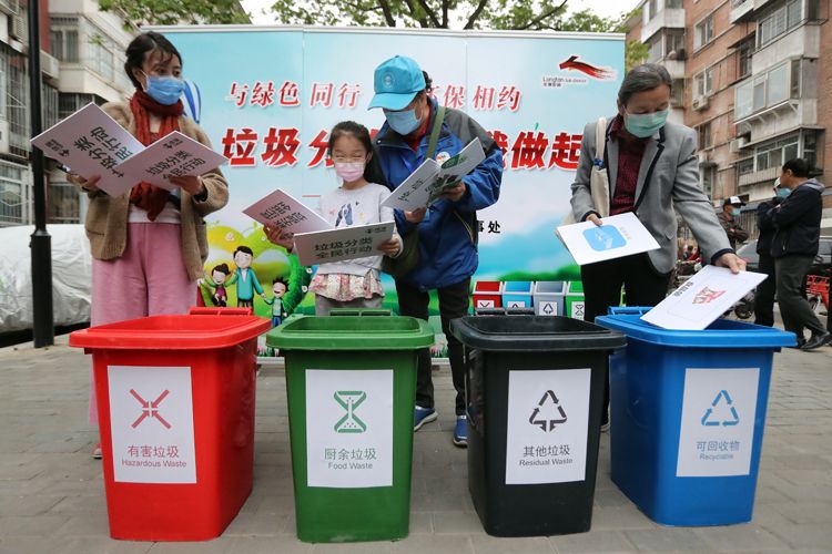 住民将手中的垃圾图卡划分投放到四色垃圾桶内。
