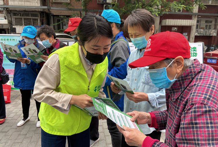 自愿者为住民发放垃圾分类宣传资料。
