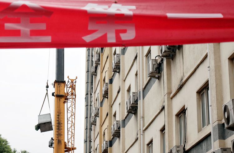  吊车将屋顶拆除的设备送至地面。