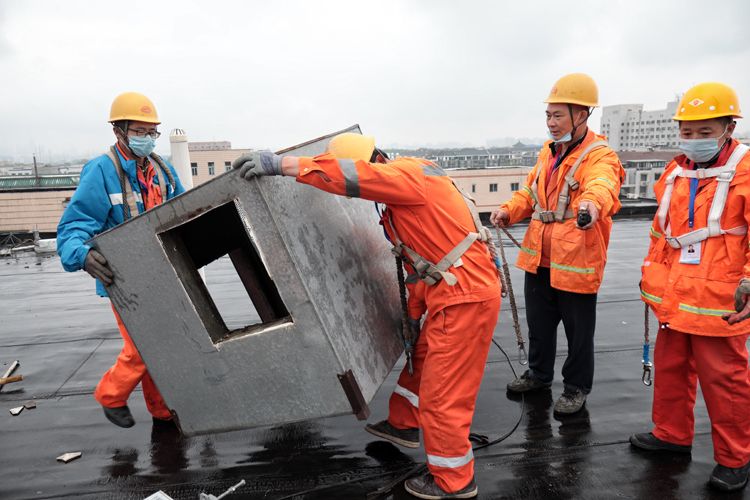  工人拆除屋顶管道设备。