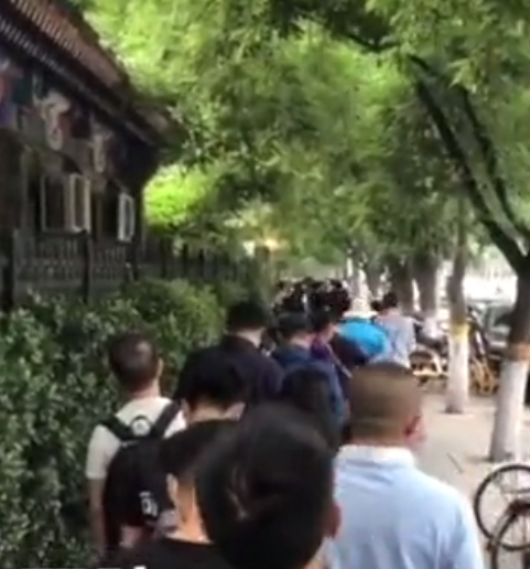 市民在医院门前排起长队。视频截图