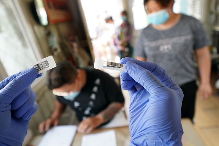 为减少聚集,市场在另一区域向商户和职工发放检测用的试管。