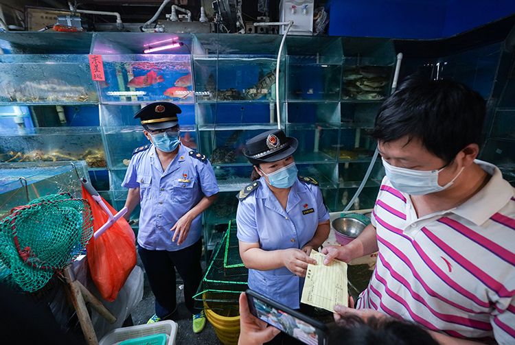在海鲜水产大厅一家摊位前,市场监管局工作人员检查商户的进货票据。