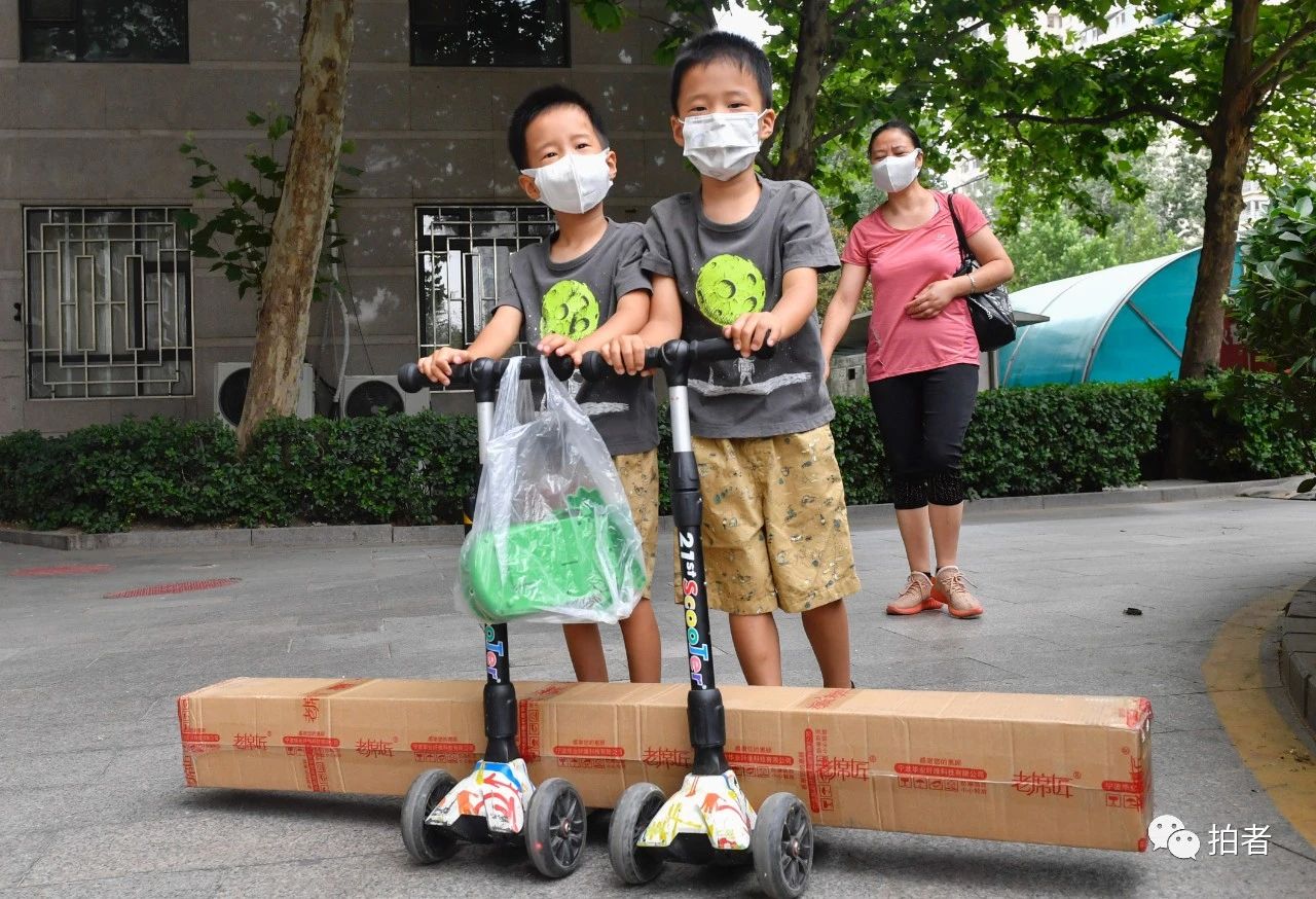 △6月17日,向阳区一小区,两名小同伙在家长的陪伴下,用滑板车取货。拍照/新京报记者吴宁