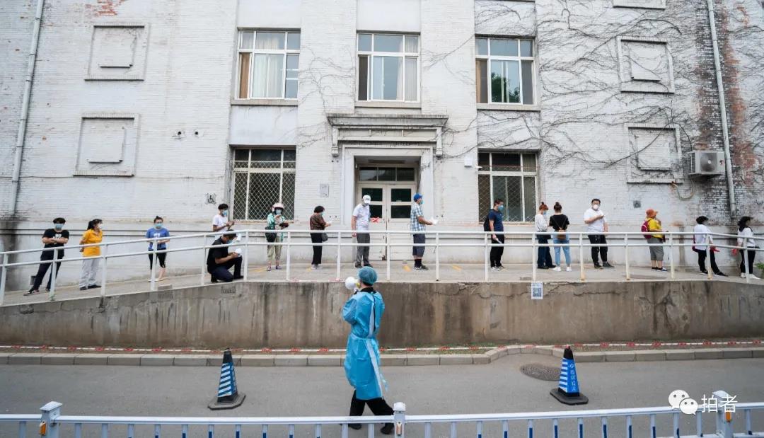 △6月17日,北京大学首钢医院,事情职员用喇叭提示前来举行核酸检测的人们保持平安间隔列队。