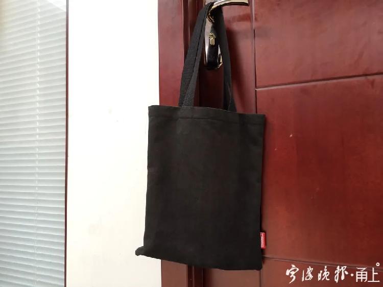 一款看似普通的黑色手提袋，角落里实则藏着一个偷拍器的摄像头。