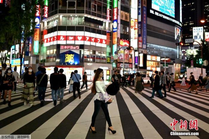 图为当地时间5月25日，人们穿过日本东京新宿区的一条街道。