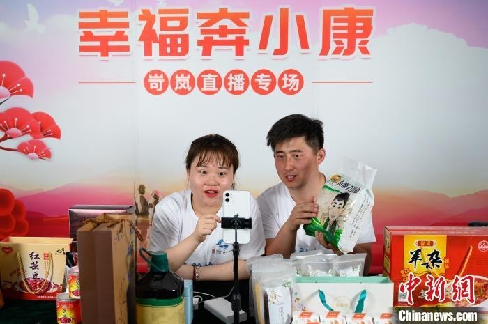 忻州市岢岚县大涧乡官庄村第一书记田亮(右)向网友推荐岢岚县农特产品。 韦亮 摄