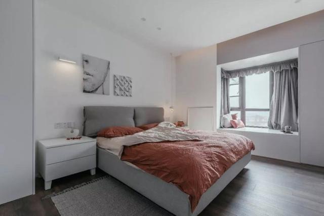 卧室也是现代极简的硬装空间,软包的床头上布置了一张橘红色的床单