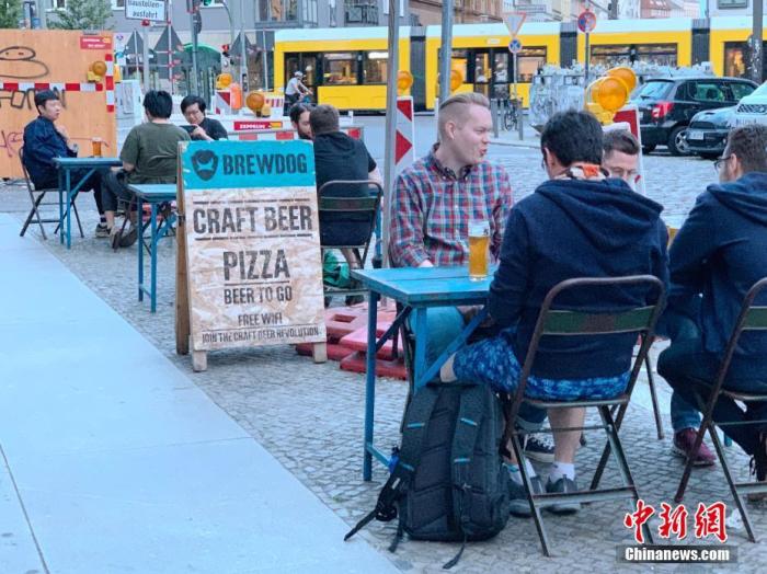 6月3日，柏林市中心一家精酿啤酒吧的顾客坐在街边饮酒。每桌顾客均保持了1.5米以上的距离。 中新社记者 彭大伟 摄