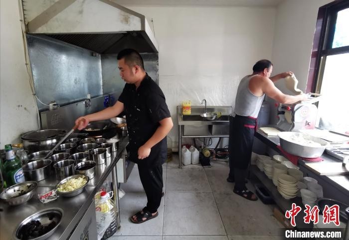 泽城村村民王浩东和父亲王光明在厨房忙碌着。 杨杰英 摄