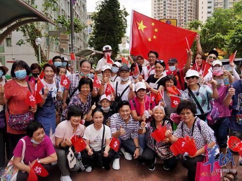 香港九龙黄大仙下邨,众多居民手拿国旗欢迎巡游花车