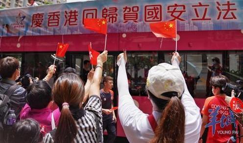 香港九龙黄大仙下邨,众多居民手拿国旗欢迎巡游花车