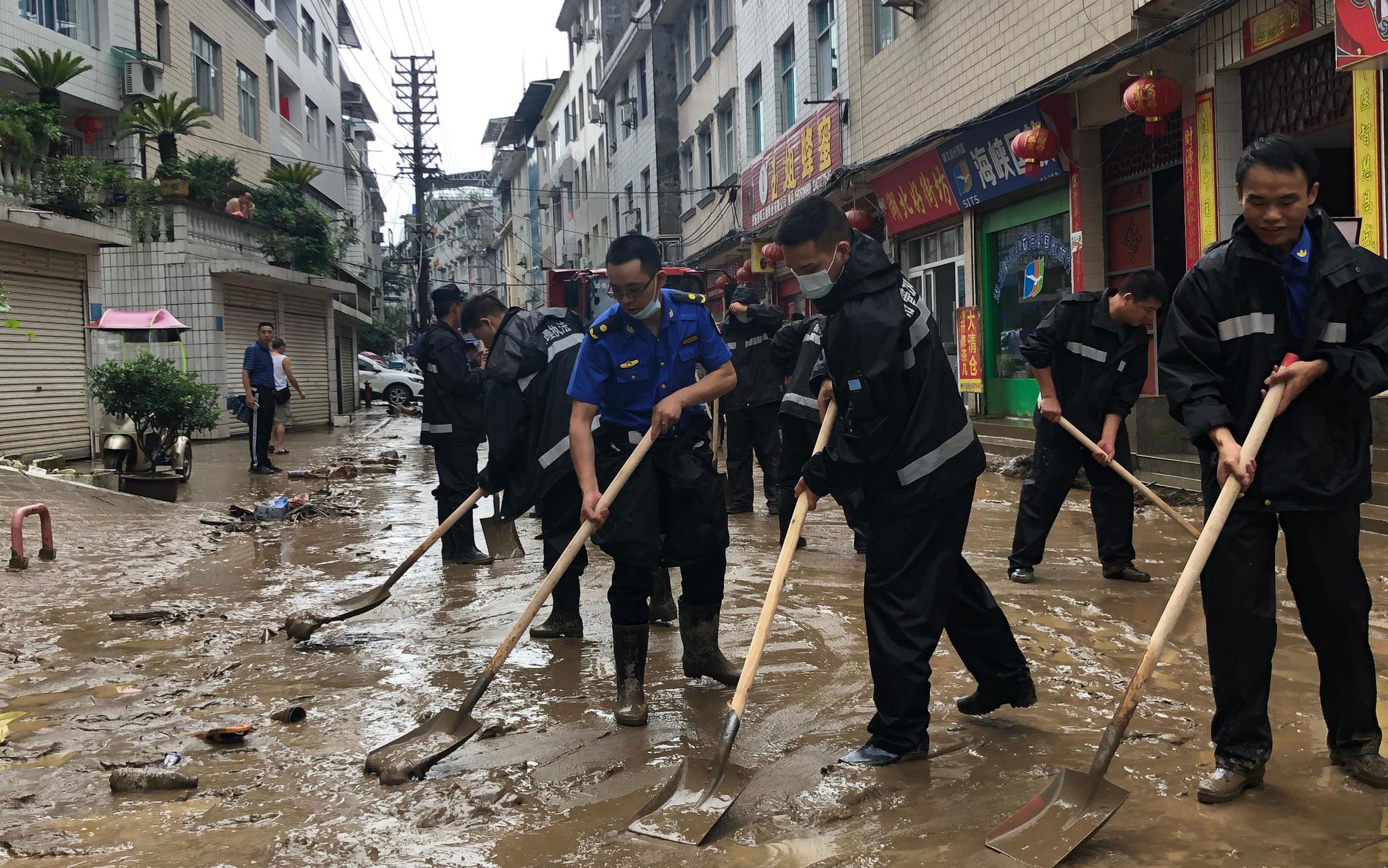7月26日，建始县城区洪水过后，工作人员运走被淹车辆。新京报记者 向凯 摄