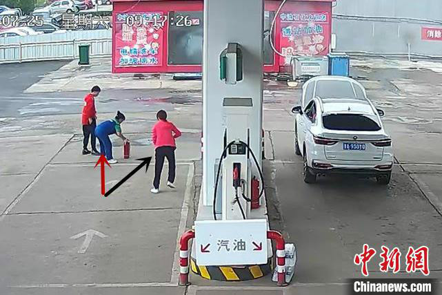 黑色箭头所指为车主,红色箭头所指为加油员,两人正准备对汽车发动机部位明火进行扑救。 视频截图