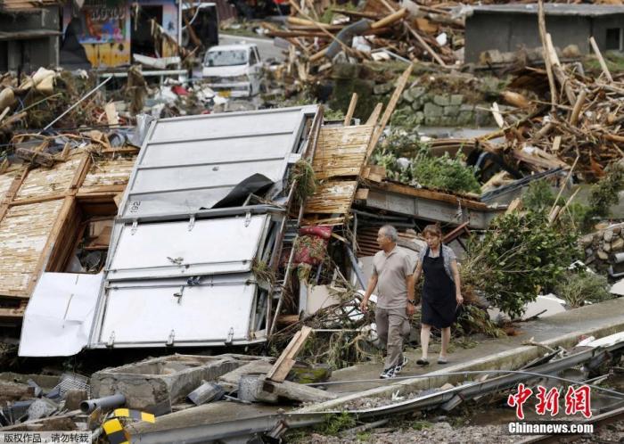  日本九州各地近日遭遇强降雨，图为熊本县一对夫妇走过被冲毁的房屋。