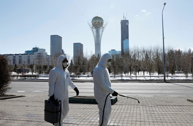 2020年3月24日,哈萨克斯坦努尔苏丹,穿防护服的事情职员在街上喷洒消毒剂防备新冠病毒流传。