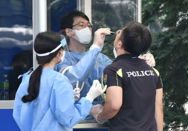 19日,医务工作者在给参加集会执勤的韩国警官做病毒检测。(法新社)