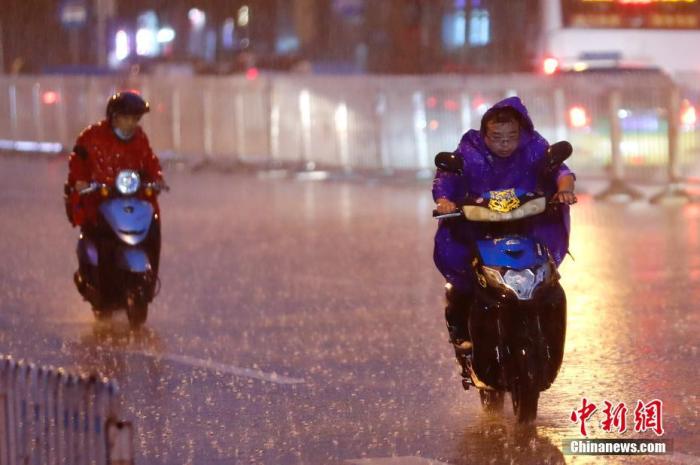 资料图:民众冒雨出行。中新社记者 盛佳鹏 摄
