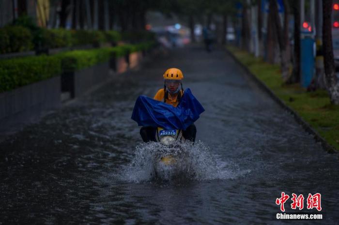 台风“森拉克”擦过海南三亚,琼岛出现强降雨天气。图为暴雨导致海口部分路段出现积水,外卖小哥冒险通过积水路段。 骆云飞 摄
