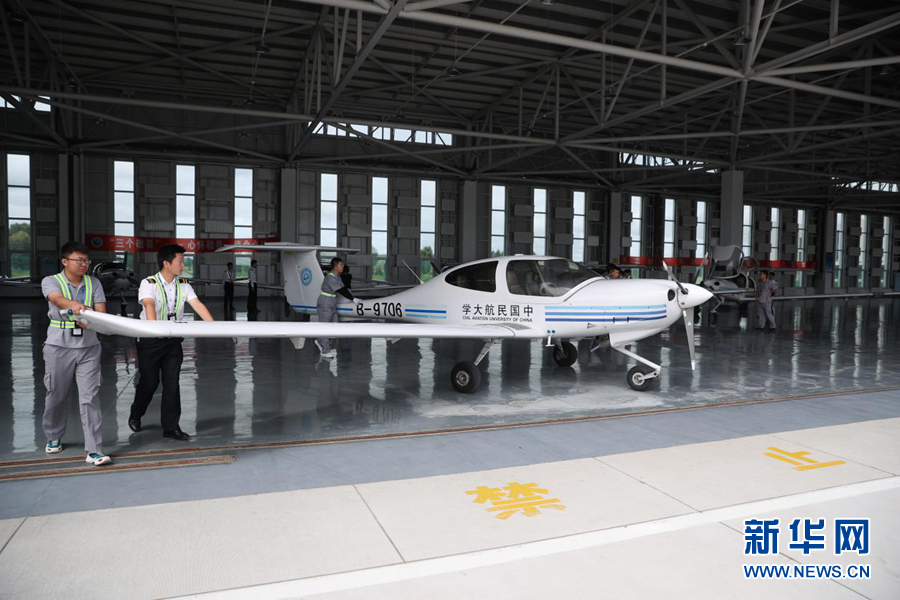 图为练习航行前航行学员和机务职员一同将练习机推出机库。新华网记者焦鹏摄