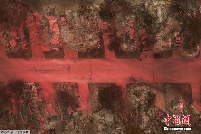 资料图:当地时间9月13日,美国俄勒冈州,当地消防喷洒红色阻燃剂扑灭阿尔梅达山火,大片的地面、多辆汽车、房屋、植被都被染红,搜救人员在废墟中寻找遇难者。
