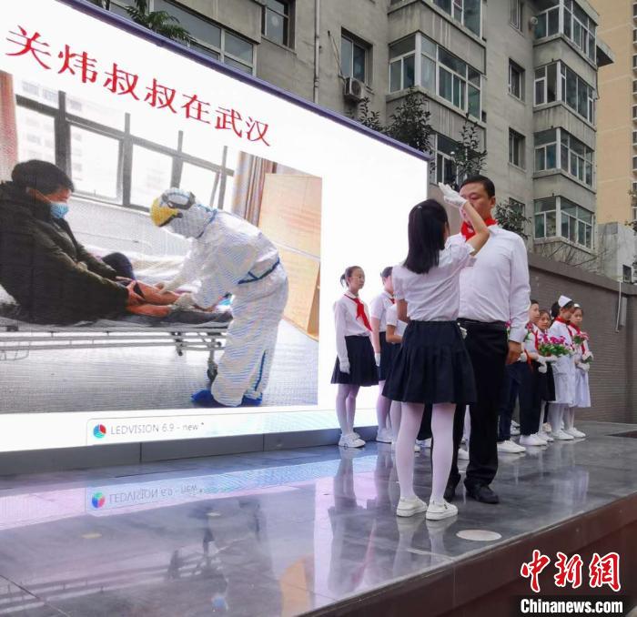 图为关子芸为自己的爸爸关炜系好红领巾。 吴琼 摄