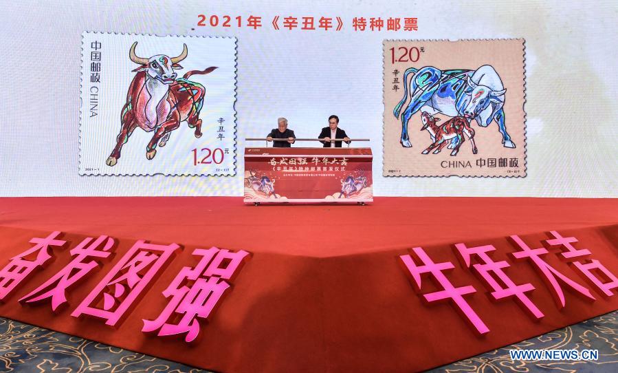 Artist Yao Zhonghua (L) and Liu Aili, chairman of China Post Group Co., Ltd., attend the issue ceremony of a set of special stamps themed on the Year of the Ox, designed by Yao, in Beijing, capital of China, Jan. 5, 2021. China Post on Tuesday issued a set of two special stamps to mark the upcoming Year of the Ox. (Xinhua/Li He)