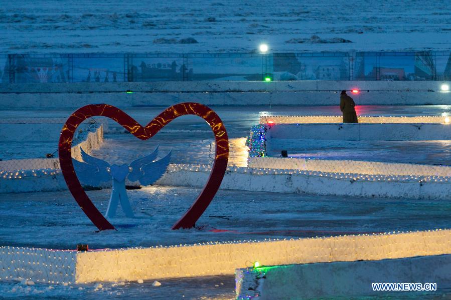 A worker installs light decorations at a winter theme park on the frozen surface of the Songhua River in Harbin, northeast China's Heilongjiang Province, Jan. 4, 2021. (Xinhua/Xie Jianfei)