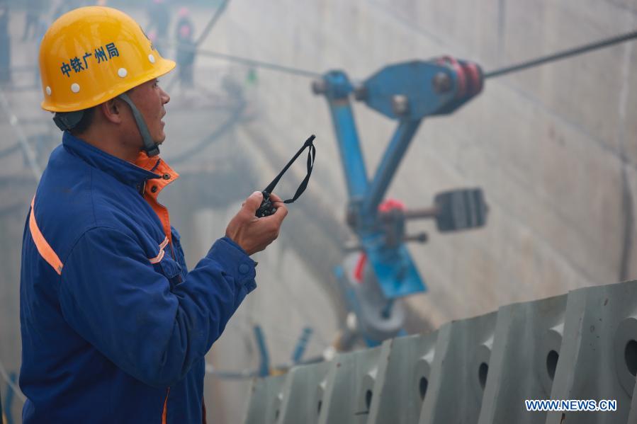 A worker takes command as his co-workers install the main cables on the Kaizhou Lake grand bridge in southwest China's Guizhou Province, Jan. 5, 2021. The Kaizhou Lake grand bridge is part of the Weng'an-Kaiyang expressway. With a main span of 1,100 meters, the bridge is 1,257 meters in length and one of its main towers is 139 meters in height. (Xinhua/Liu Xu)