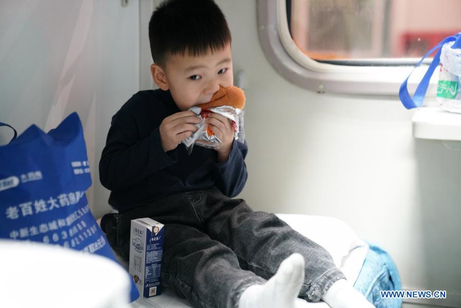 A child eats bread on train K7093 running from Harbin, northeast China's Heilongjiang Province to Hailar, north China's Inner Mongolia Autonomous Region, Jan. 6, 2021. Train No. K7093/4, connecting Harbin and Hailar, runs a distance of 1,320 kilometers and stops at 52 stations during the about 26-hour trip. The train stops every 30 minutes on average due to so many stops and is known as the slowest train in the forest area between the two destinations. Having operated for over 30 years, the train's facilities have witnessed upgrade and created a cozy environment for passengers. (Xinhua/Wang Jianwei)