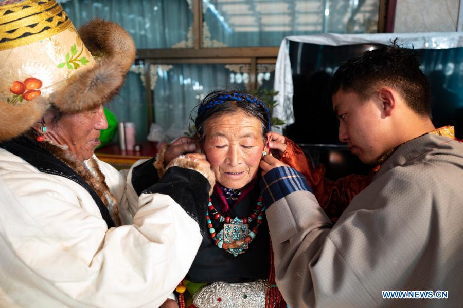 Villager Butri (C) has her earrings on in her new house to celebrate farmers' New Year in Gajilin Village of Chaqiug Township in Sa'gya County of Xigaze, southwest China's Tibet Autonomous Region, Jan. 14, 2021. Residents who were relocated from poverty-stricken area celebrate the farmers' New Year in their new homes in Gajilin Village. In Xigaze and other farming regions of Tibet, people celebrate New Year on the 1st day of the twelfth month of the Tibetan lunar calendar. According to local farming tradition, spring ploughing season always begins as the fall of New Year, thus celebrating one month earlier is to meet the needs of local agriculture. Xigaze City is regarded as a granary of Tibet. (Xinhua/Purbu Zhaxi)